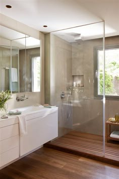 a bathroom with a shower, sink and wooden floor in it's own area