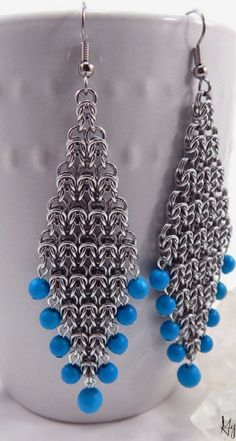 a pair of earrings with blue beads hanging from it's earwires on a white cup