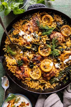 a skillet filled with pasta and meat covered in cheese, herbs and lemons