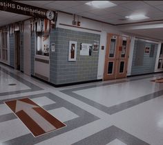 an empty hallway in a school with blue and white tiles on the floor, red arrow painted on the floor