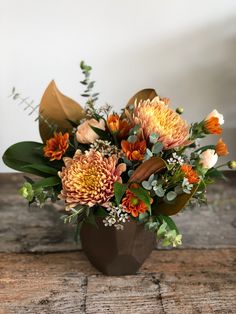 a vase filled with lots of flowers on top of a wooden table