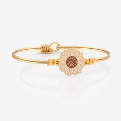 Say hello to our Golden Cream Sunflower Bangle Bracelet! Grow in loyalty and love like sunflowers towards the light. The creamy color brings a touch of golden hour sunshine to your fall style! Cream Sunflower in Semi Bright 12KT Gold Plated finish Brass bangle with L+D logo tag Easy hook and catch closure Oval shape to ensure proper fit Regular, Petite, or Large sizing options Packaged in a gift box and includes an essence card Handcrafted in the USA Yellow Gold Bangle Charm Bracelet For Gift, Adjustable Gold Jewelry With Sunflower Design, Elegant Yellow Gold Bracelet With Flower Charm, L D Logo, Sunflower Charm Bracelet, Elegant Gold Plated Flower-shaped Bracelet, Golden Bracelet, D Logo, Creamy Color