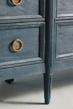 a blue dresser with brass knobs on it's handles and drawers, against a white background