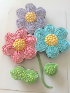 three flower shaped cupcakes sitting on top of a white table next to each other