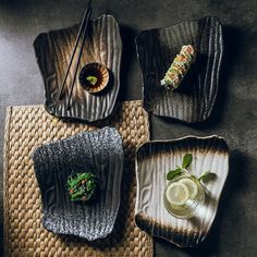 three plates with different foods on them sitting on a place mat next to chopsticks