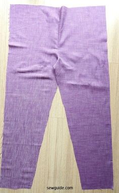 a pair of purple leggings sitting on top of a wooden floor next to a piece of cloth