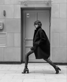 black and white photograph of a woman walking in front of a door with her foot on the ground