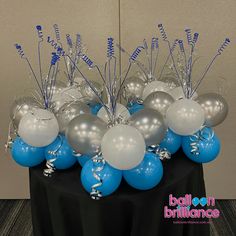 balloons and streamers are arranged on a table for a balloon decorating contest in blue and silver