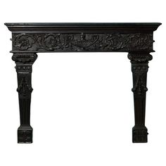 an ornately carved fireplace mantel with carvings on the top and sides, in black