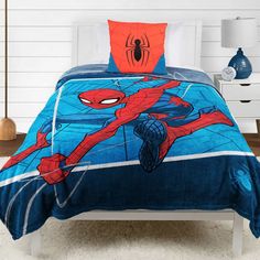 a bed with spiderman comforter and pillows