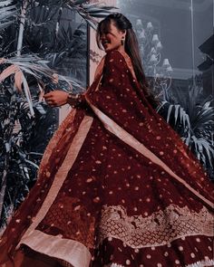 a woman standing in front of a tree wearing a red and white dress