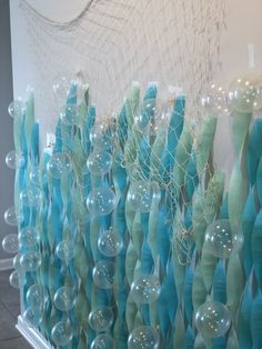 there are many blue and green vases hanging on the wall with bubbles in them