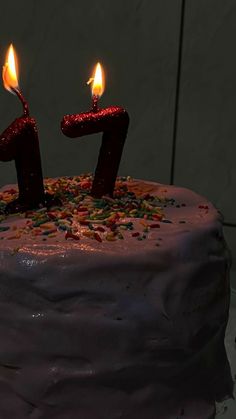 a birthday cake with two candles that are lit and sprinkles on it