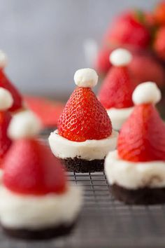 some chocolate cupcakes with strawberries on top are decorated like santa's hats