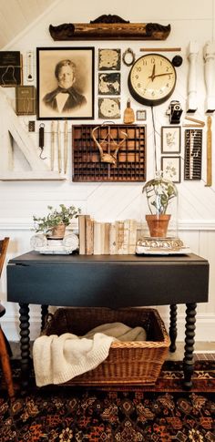 a black table sitting in front of a wall filled with pictures and clocks on it