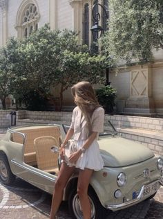 a woman sitting on the back of an old car