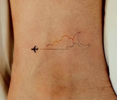 a small tattoo on the side of a woman's leg with an airplane flying in the sky