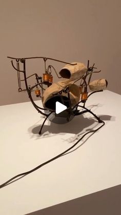 a sculpture made out of wood and wire on top of a white table with a black cord