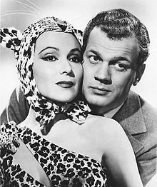 an old photo of a man and woman in animal print clothes with one holding the other's head