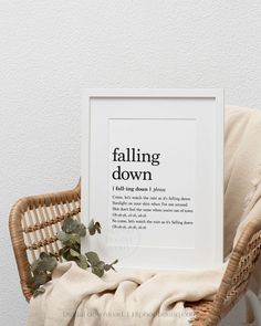 a white framed print sitting on top of a wicker chair next to a plant