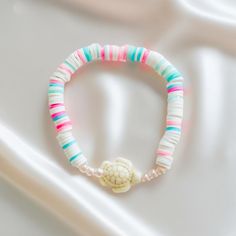 a bracelet with a shell and beads on it sitting on top of a white surface