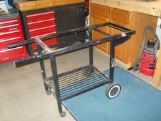 a black cart sitting in a garage next to a workbench with tools on it