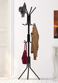 a coat rack with hats and purses on it in front of a white wall