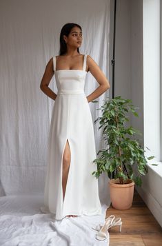 a woman standing in front of a window wearing a white dress