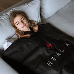 a woman laying on top of a couch holding a black bag