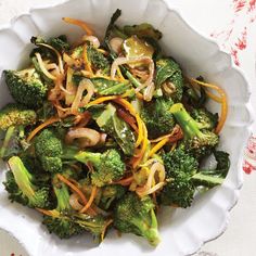 a white bowl filled with broccoli and onions on top of a table cloth