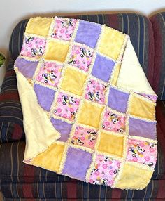 a couch with a blanket on top of it next to a vase filled with flowers