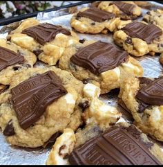 chocolate chip cookies and marshmallows are arranged on a baking sheet in preparation to be eaten