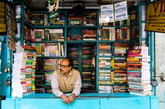 a man sitting in the window of a book store with many books on display behind him