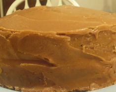 a close up of a frosted cake on a plate with a chair in the background