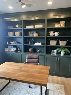 a room with green bookcases and a wooden table