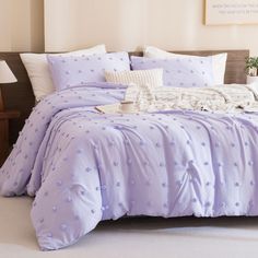 a bed with purple comforter and pillows on it