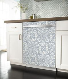 a kitchen with white cabinets and blue patterned backsplash