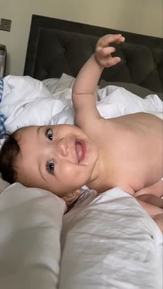 a smiling baby laying on top of a bed