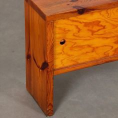 a wooden bench with two drawers on the bottom and one drawer at the top that has holes in it