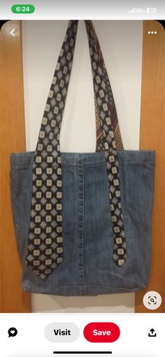 a denim bag with a tie on it hanging from a hook in a wall next to a wooden door