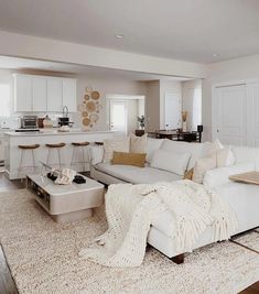 a living room filled with white furniture and lots of pillows on top of a rug