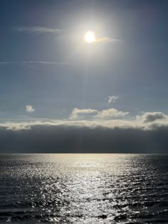 the sun is shining over the ocean on a clear day with some clouds in the sky