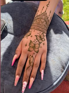 a woman's hand with henna tattoos and pink nail polishes on it