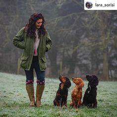 a woman standing in the grass with three dogs