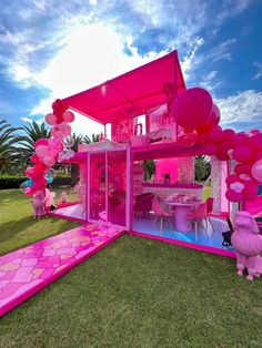 a pink house with balloons and decorations on the lawn