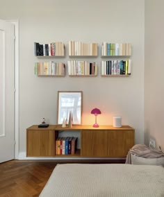 a bedroom with a bed, bookshelf and lamp on the wall above it