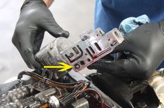 a person in black gloves working on an engine