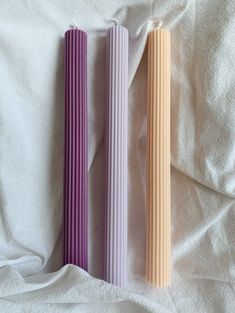 two different colored straws laying on top of a white bed sheet next to each other