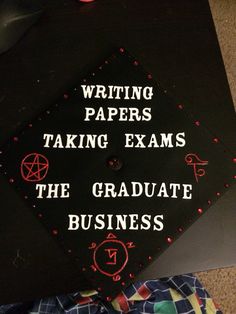 a black graduation cap with writing papers taking exam the graduate business is written on it