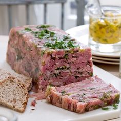 a meatloaf sandwich cut in half on a plate next to bread and water